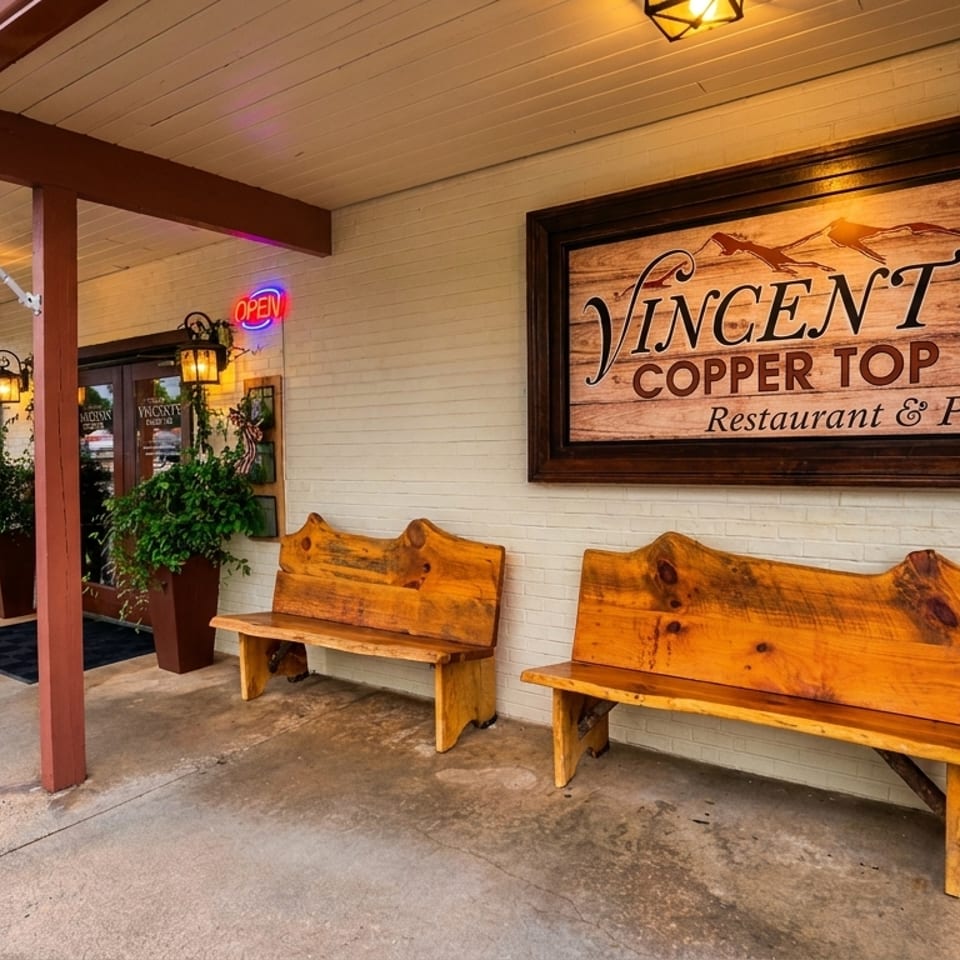Exterior of Vincent's Copper Top Restaurant & Pub with a sign, benches, and an American flag.