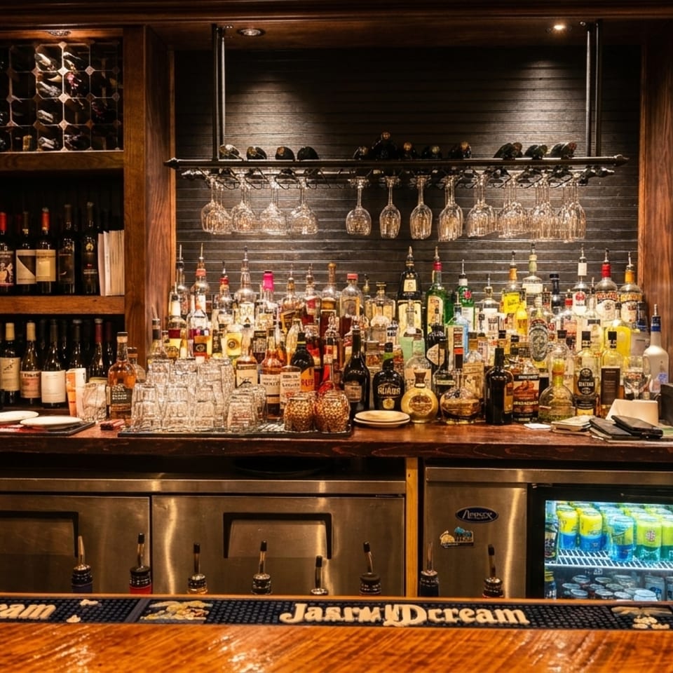 A fully stocked bar with various liquor bottles, wine racks, hanging glasses, and a POS system.